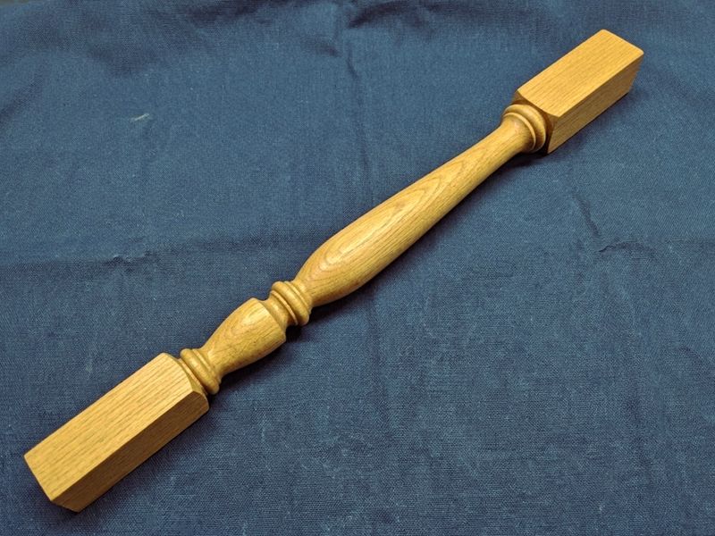 The same spindle from a second angle on navy cloth, showing the stained finish.